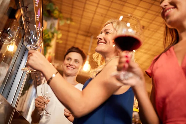 Glada kvinnor hälla vin från dispenser på bar — Stockfoto