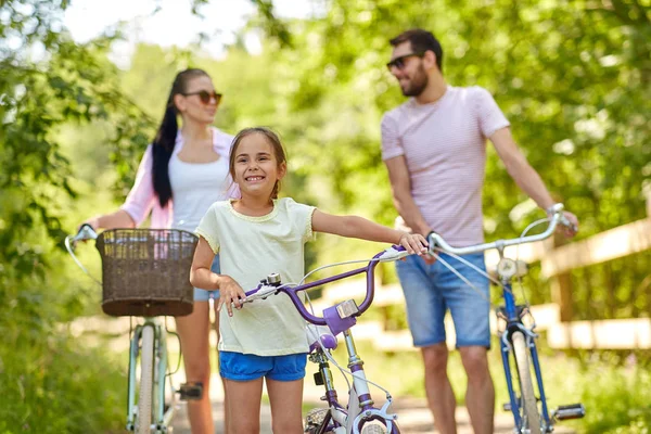 Счастливая семья с велосипедами в летнем парке — стоковое фото