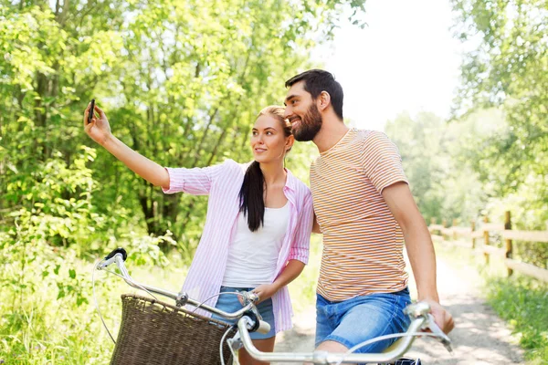 与骑自行车的夫妇用智能手机自拍 — 图库照片