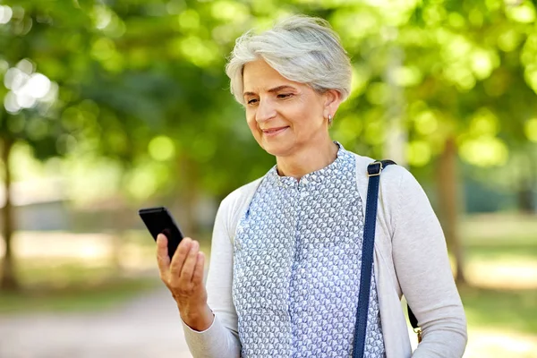 Happy senior woman with smartphone at summer park — Stock Photo, Image