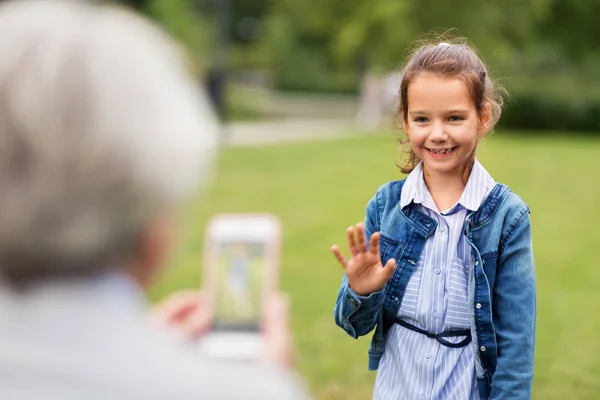 Маленька дівчинка фотографується в літньому парку — стокове фото