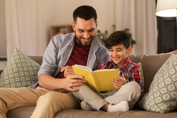 Pai feliz e filho ler sofá livro em casa — Fotografia de Stock