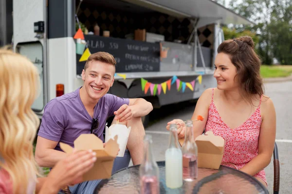 Happy friends with drinks eating at food truck — Stock Photo, Image