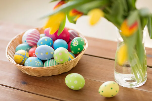 Uova di Pasqua colorate in cesto e fiori a casa — Foto Stock