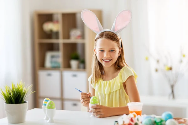 Happy girl coloring easter eggs at home — Stock Photo, Image