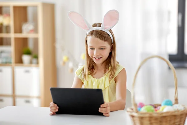 Menina feliz com tablet pc e ovos de Páscoa em casa — Fotografia de Stock