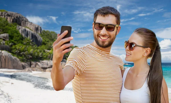 Feliz pareja tomando selfie por teléfono inteligente en la playa —  Fotos de Stock