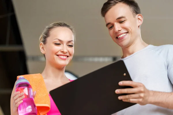 Frau und Personal Trainer mit Klemmbrett im Fitnessstudio — Stockfoto