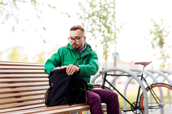 Homem ou hipster com mochila no banco de rua — Fotografia de Stock