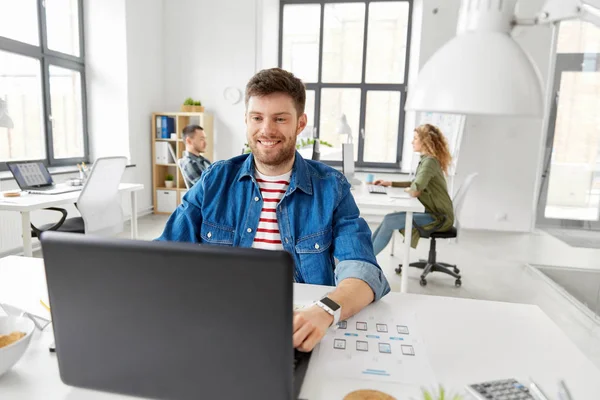 Sonriente hombre creativo con portátil de trabajo en la oficina —  Fotos de Stock