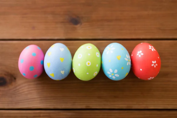 Fila di uova di Pasqua colorate sul tavolo di legno — Foto Stock