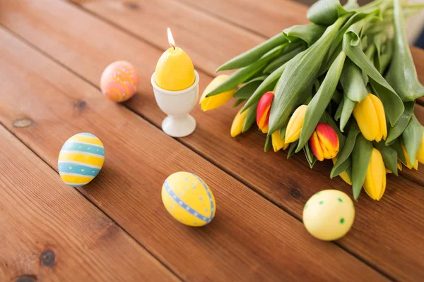 Vela en forma de huevo de Pascua y flores de tulipán — Foto de Stock