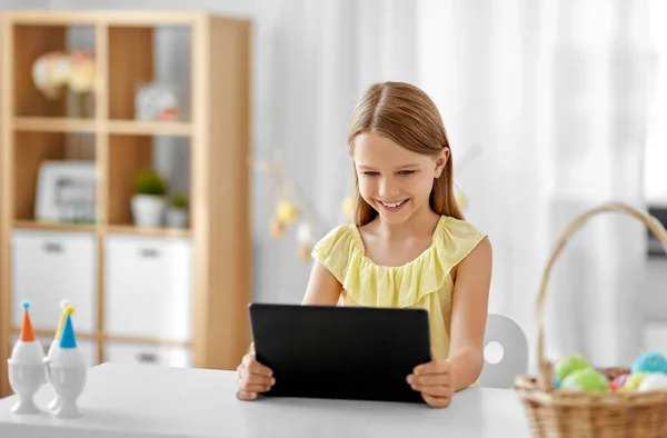 Счастливая девочка с планшетным компьютером и съедобными яйцами дома — стоковое фото