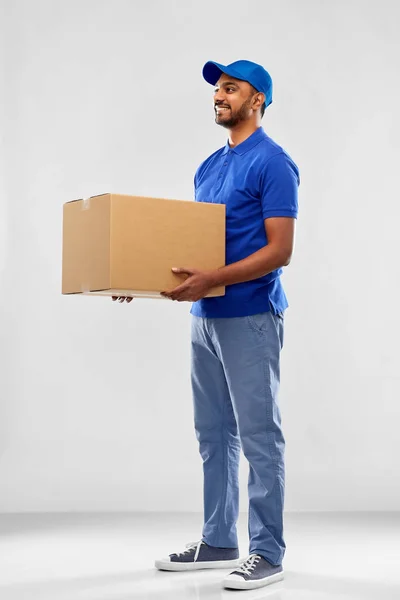 Homem de entrega indiana feliz com caixa de pacote em azul — Fotografia de Stock