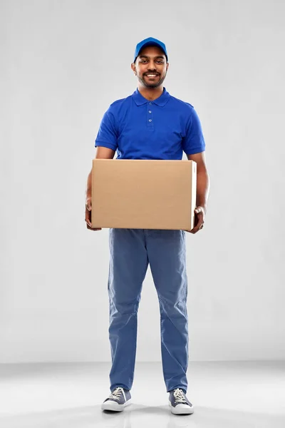 Happy indian delivery man with parcel box in blue — Stock Photo, Image