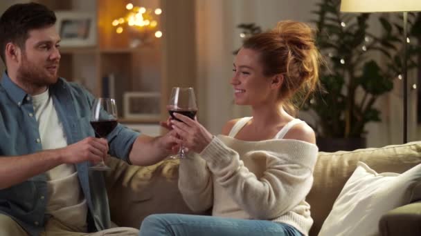 Gelukkige paar drinken van rode wijn thuis in avond — Stockvideo