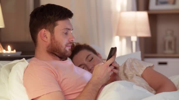 Mann benutzt Smartphone, während Freundin schläft — Stockvideo