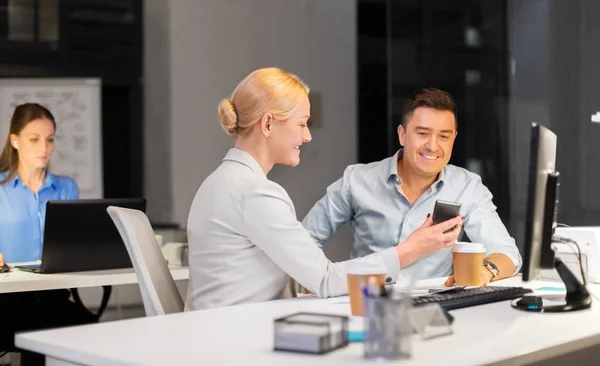 Forretningsfolk med smarttelefon på kveldskontoret – stockfoto