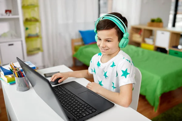 Jongen in hoofdtelefoon spelen video game op laptop — Stockfoto