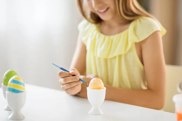 Close up of girl coloring easter egg by paintbrush — Stock Photo, Image