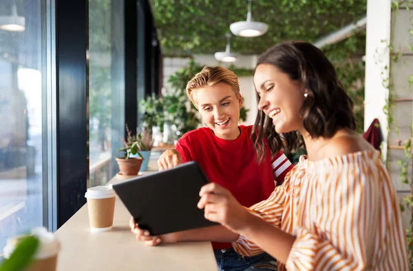 Amigos do sexo feminino com tablet pc e café no café — Fotografia de Stock