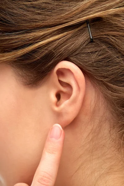 Close up of young woman pointing finger to her ear — Stock Photo, Image