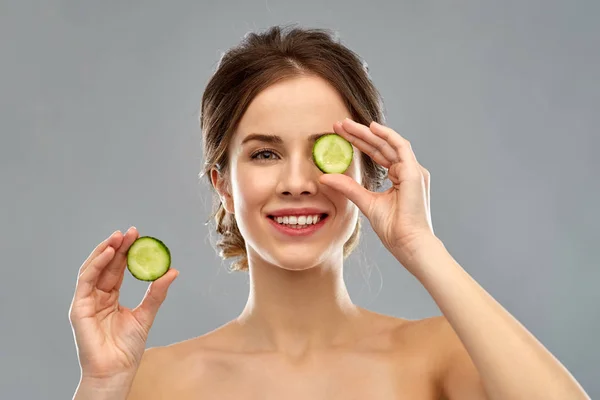 Smiling woman with cucumber over grey background — Stock Photo, Image