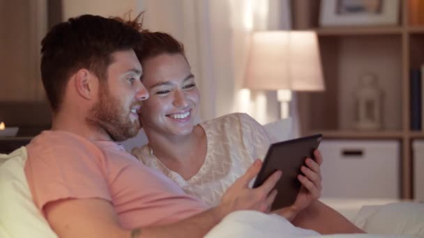 Casal feliz usando computador tablet na cama à noite — Vídeo de Stock