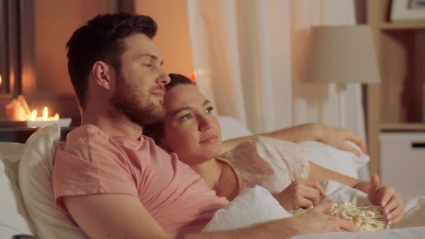 Ευτυχισμένο ζευγάρι βλέποντας τηλεόραση στο κρεβάτι τη νύχτα στο σπίτι — Αρχείο Βίντεο