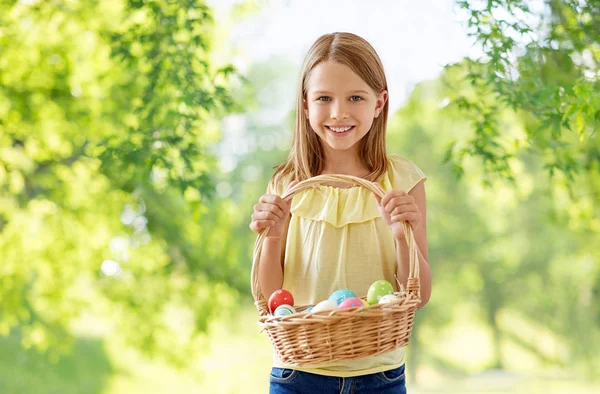 Happy girl with colored eggs in wicker basket — Stock Photo, Image