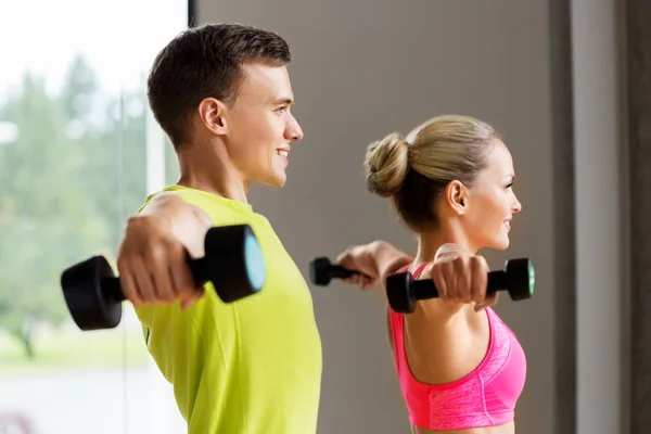 Casal com halteres exercitando no ginásio — Fotografia de Stock