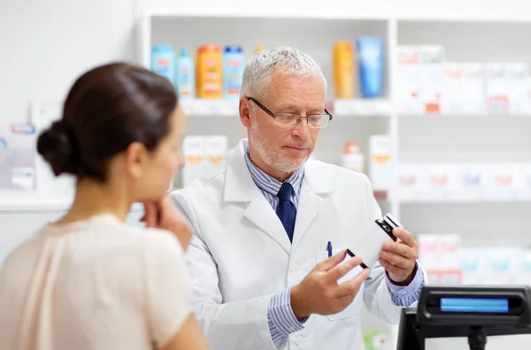 Apotheker met geneesmiddel en klant in de apotheek — Stockfoto