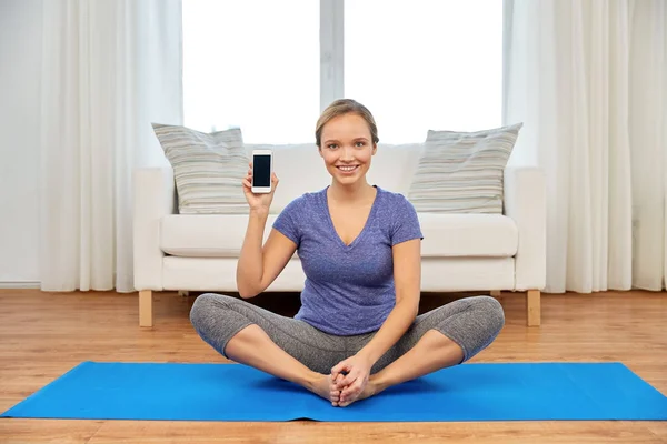 Mulher com smartphone fazendo ioga em casa — Fotografia de Stock