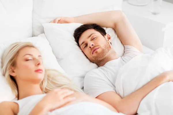 Счастливая пара спит в постели дома — стоковое фото