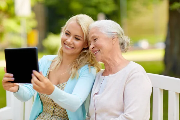 Hija con tableta PC y madre mayor en el parque — Foto de Stock