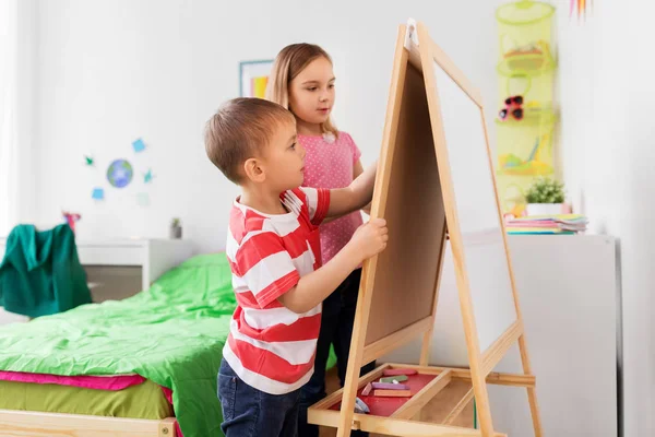 Bambini felici che disegnano su cavalletto o flip board a casa — Foto Stock