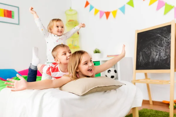 Glada lilla barn ha roligt i sängen hemma — Stockfoto