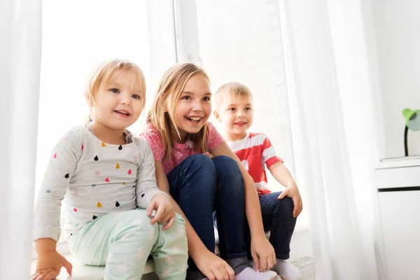 Heureux petits enfants assis sur le rebord de la fenêtre — Photo