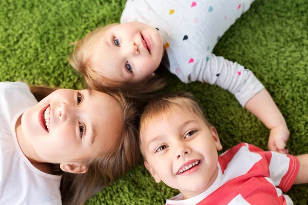 Niños pequeños y felices tumbados en el suelo o la alfombra —  Fotos de Stock