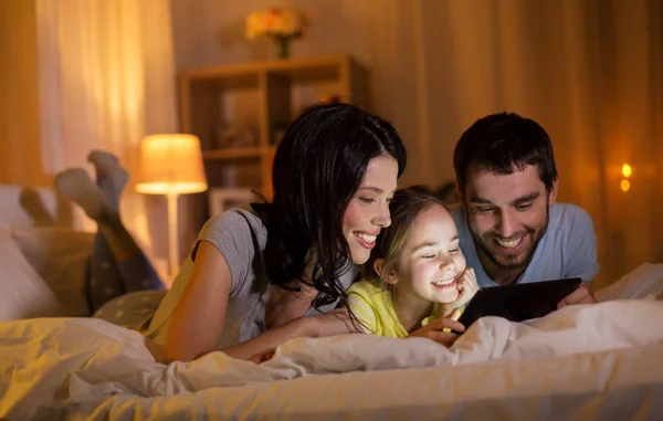 Familia con tableta pc en la cama por la noche en casa —  Fotos de Stock