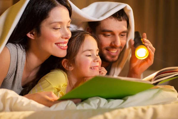 Glückliche Familie liest Buch nachts zu Hause im Bett — Stockfoto