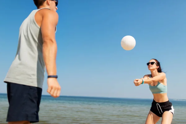 Feliz pareja jugando voleibol en la playa de verano — Foto de Stock