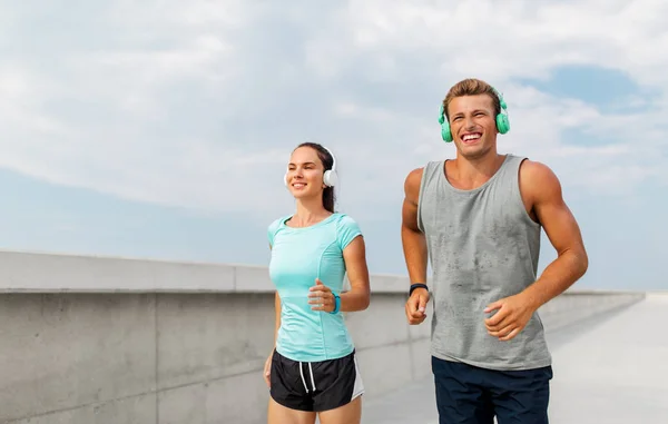 Pareja con auriculares corriendo al aire libre — Foto de Stock