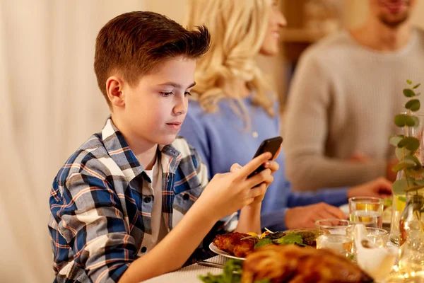 Ragazzo con smartphone alla cena in famiglia — Foto Stock
