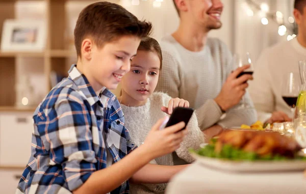 Мальчик с сестрой с помощью смартфона на семейном ужине — стоковое фото