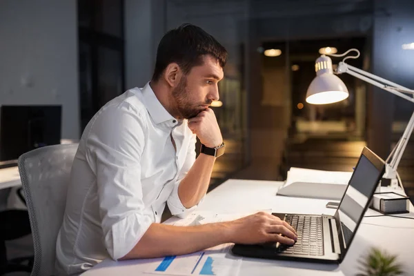 Бизнесмен с ноутбуком работает в ночном офисе — стоковое фото