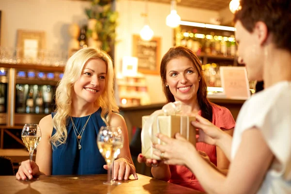Mujeres dando regalo a un amigo en el bar de vinos —  Fotos de Stock