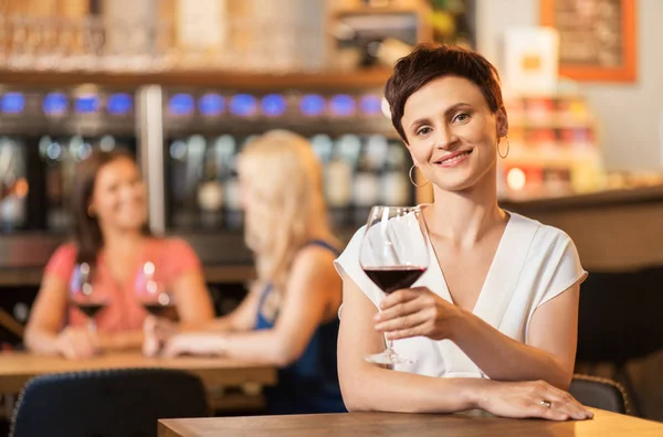 Femme heureuse buvant du vin rouge au bar ou au restaurant — Photo