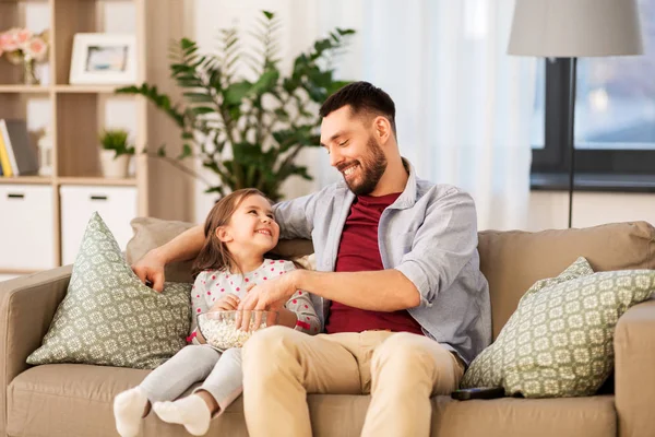 Happy father and daughter eating popcorn at home — Stock Photo, Image