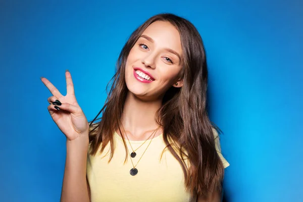 Jonge vrouw of tienermeisje vredesteken tonen — Stockfoto